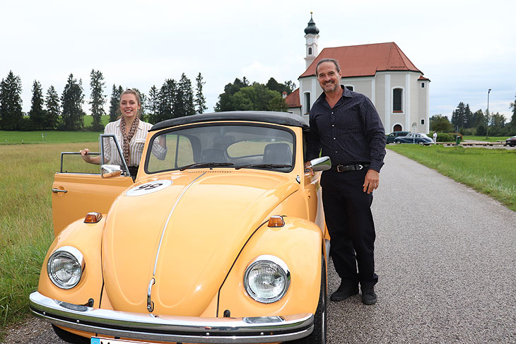 Stefanie Liebl unterwegs  mit US-Schauspieler Daryl Jackson unterweg in einem VW Käfer Cabriolet BJ 1970 von „Automobile Meilensteine“, hier vor der Wallfahrtkirche St. Leonhard in Dietramszell (©Foto. Martin Schmitz)
